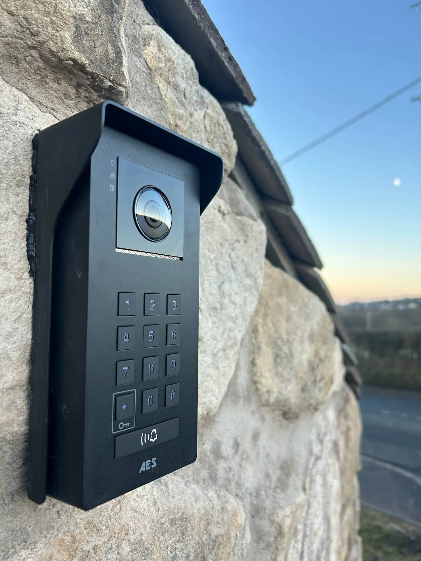 AES Global Ltd video intercom on a stone wall at dusk by KLR Design Limited