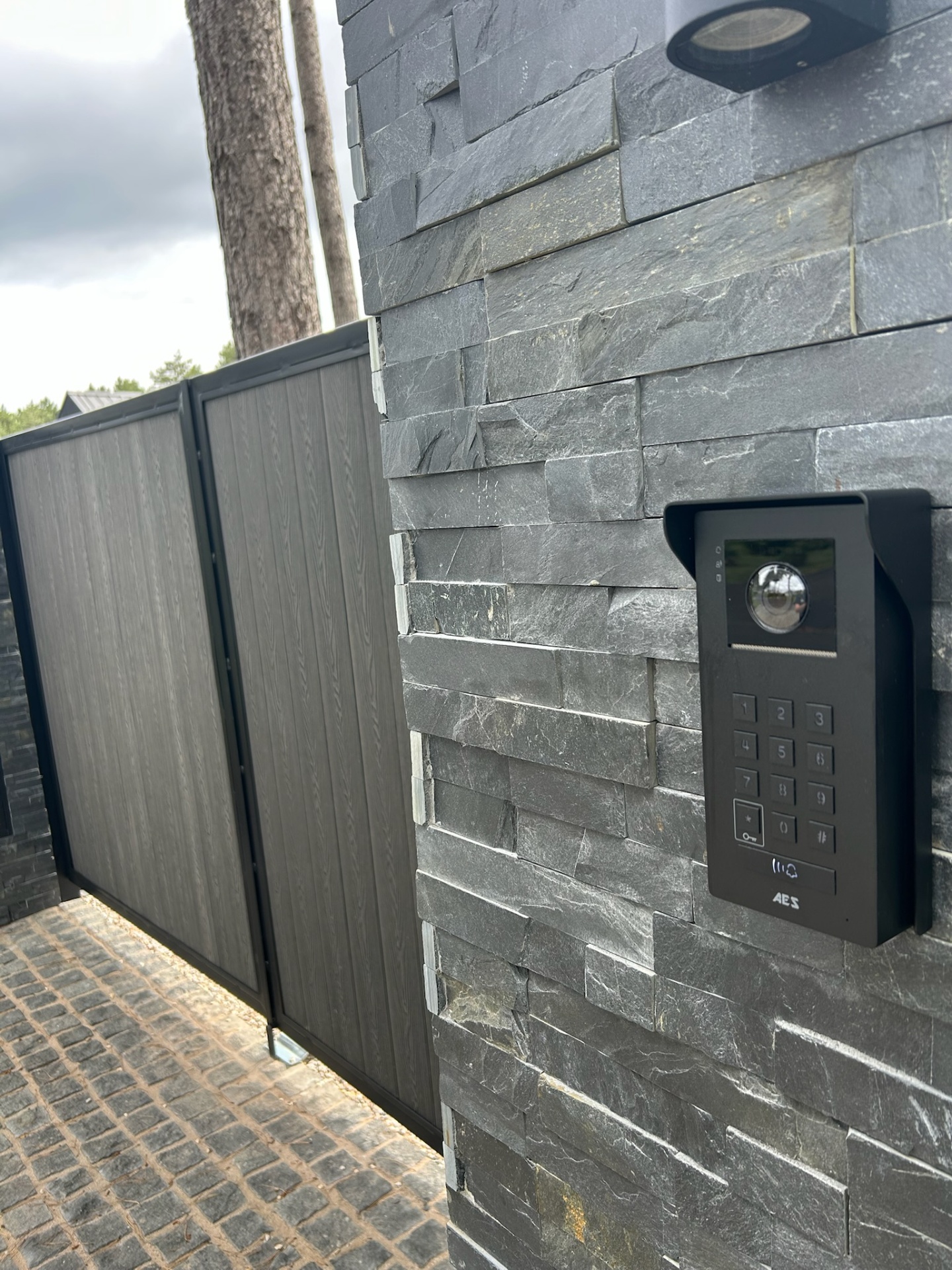 Composite gate with AES Global video intercom and keypad mounted on a stacked-stone pillar by KLR Design Limited