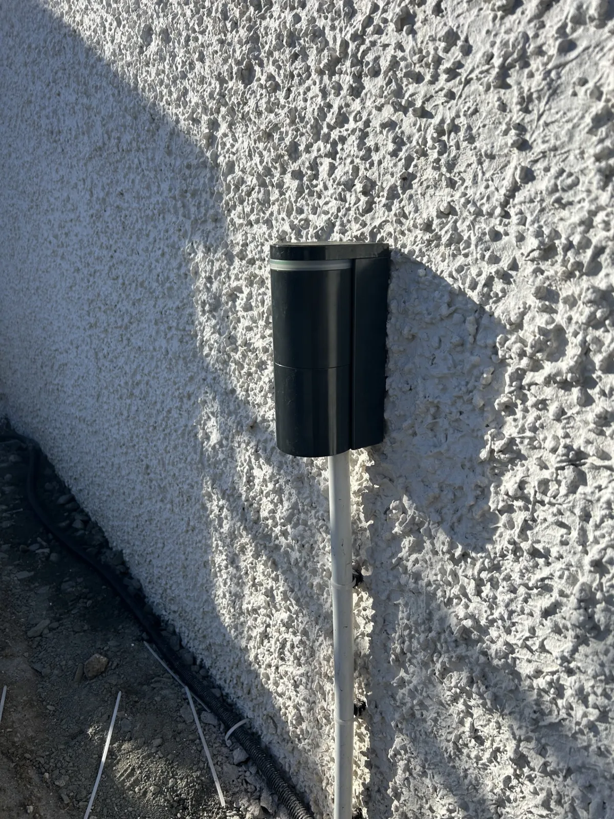 Black Optex vehicle detector on a rendered wall integrated with gate automation and intercom access by KLR Design Limited
