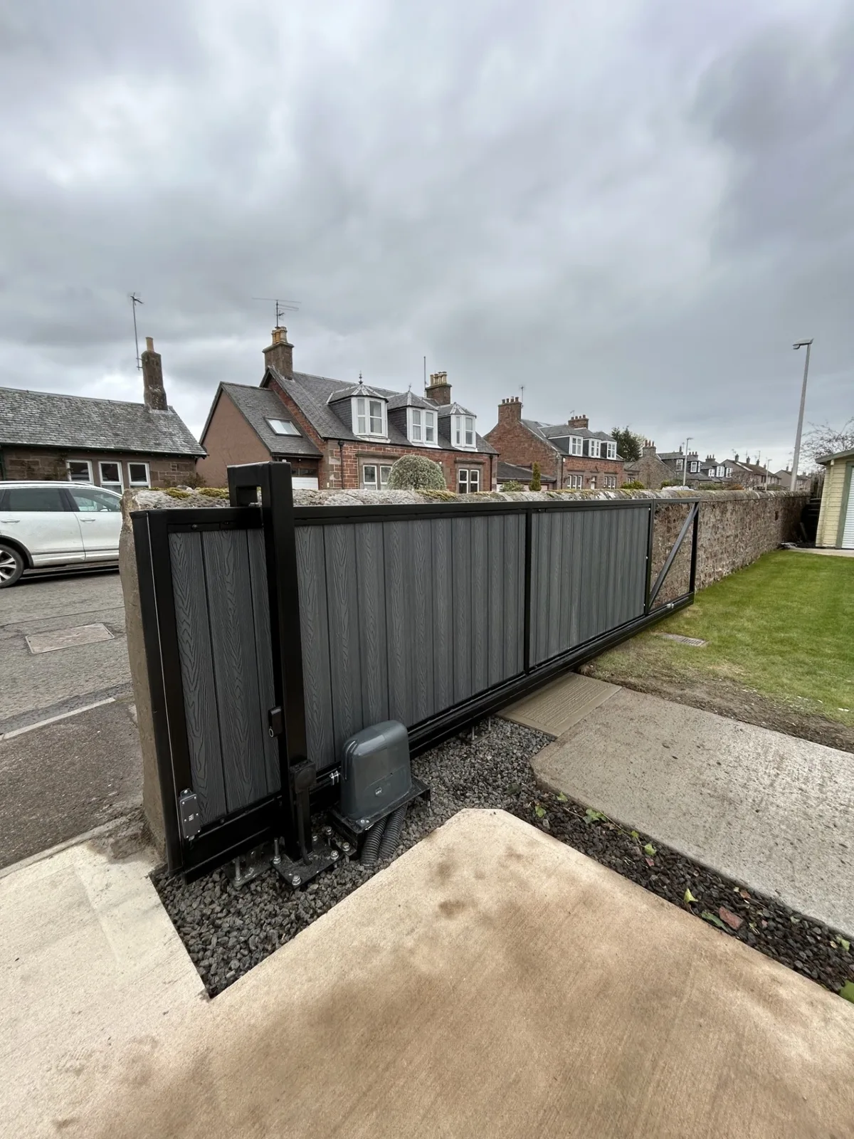Grey composite sliding gate, roadside entrance Grey composite sliding gate with KEY Automation motor on a street entrance by KLR Design Limited
