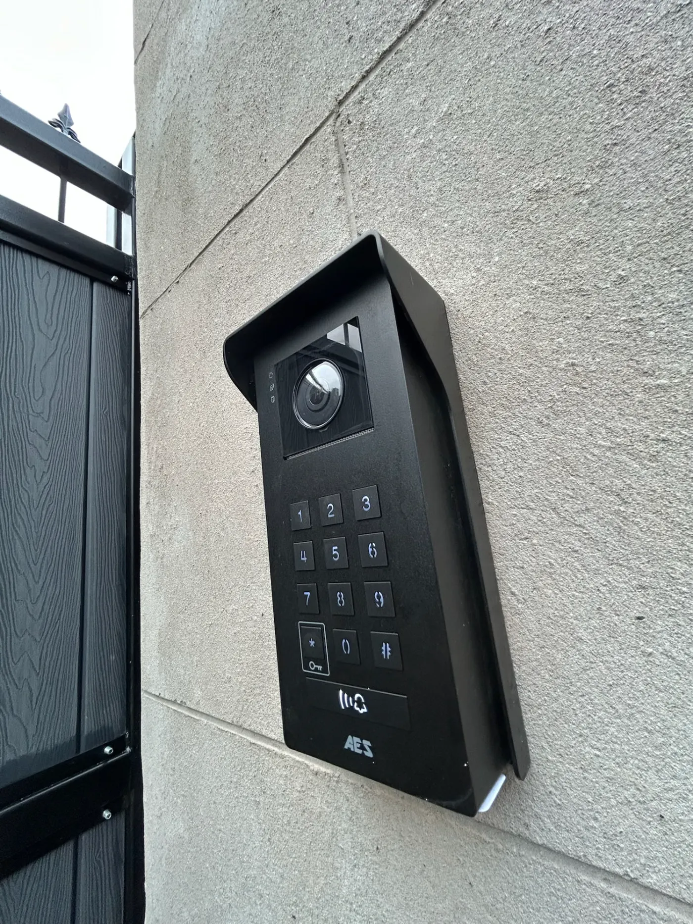 AES Global Ltd video intercom and keypad beside an electric gate installed by KLR Design Limited