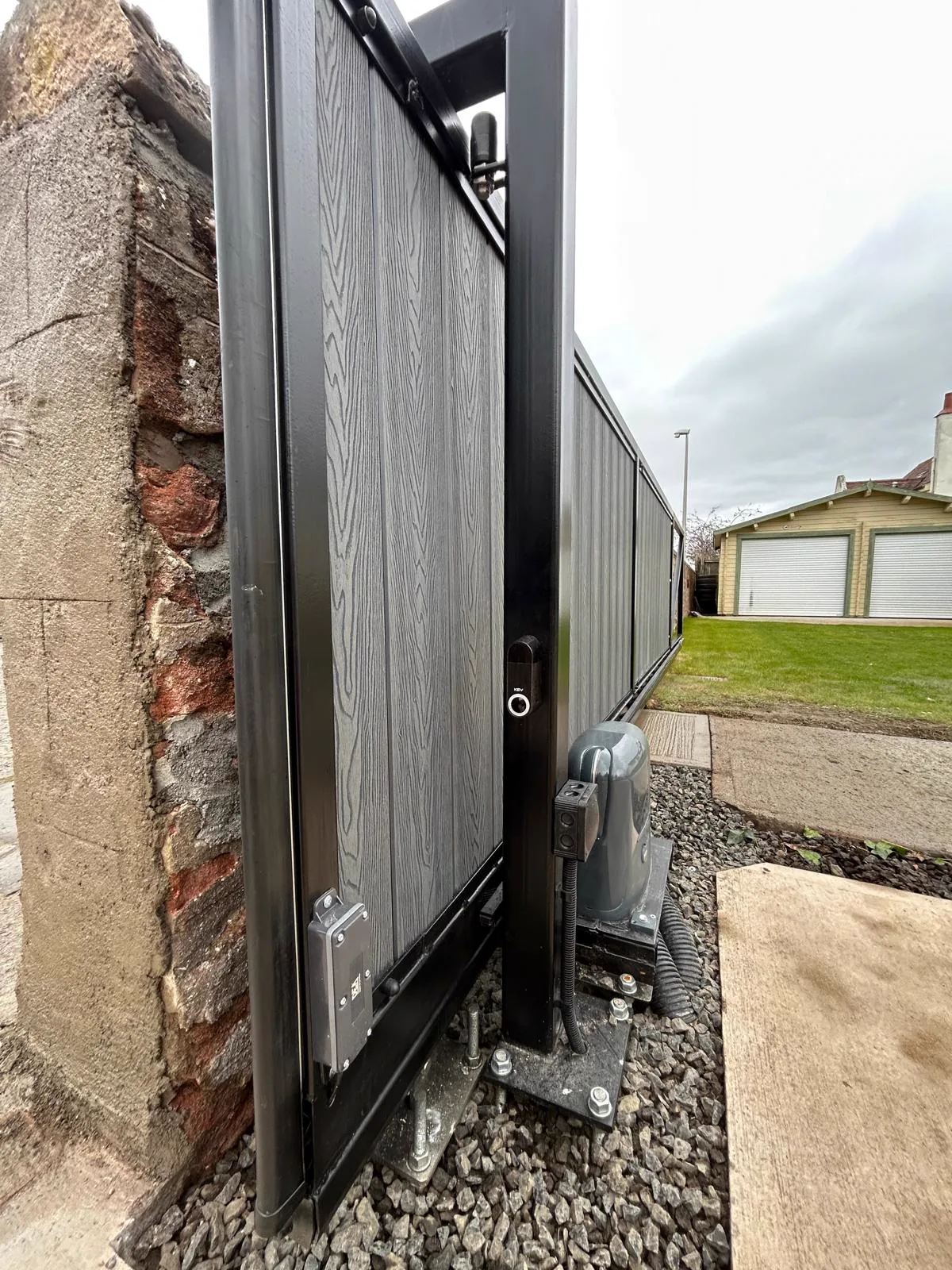 Open composite sliding gate showing KEY underground/side motor installation by KLR Design Limited