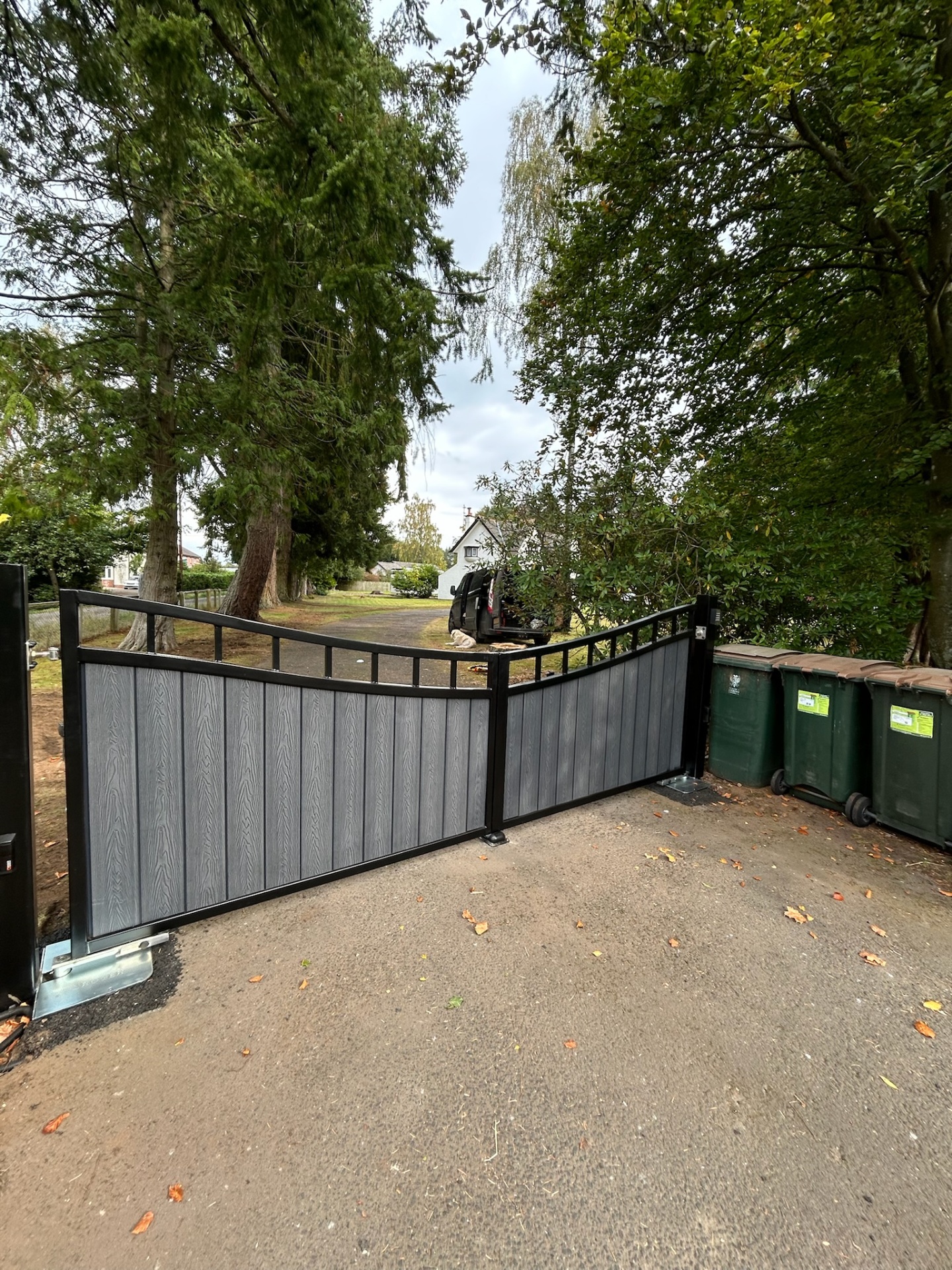 Grey composite electric swing gates with black steel frame and underground motors — angled view of a rural driveway installation in Dumfries and Galloway by KLR Design Limited