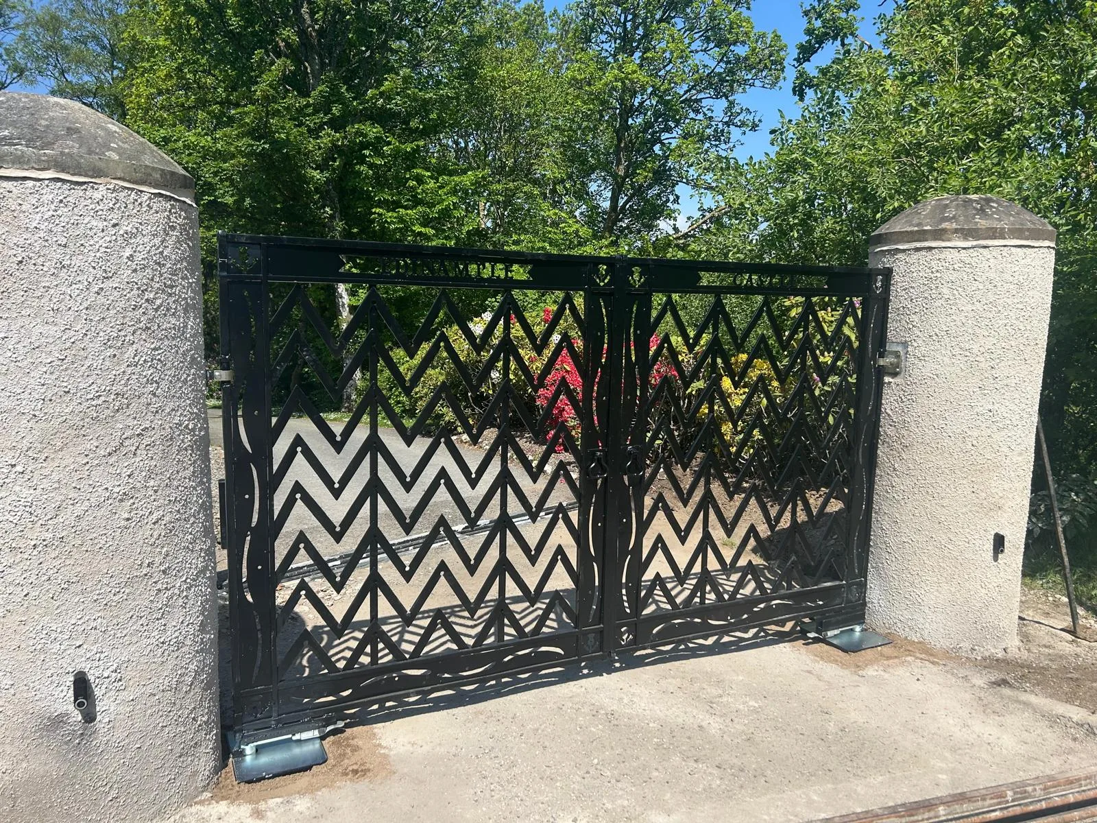 Bespoke chevron-pattern entrance gates closed between original stone castle pillars at Edinample Castle, Lochearnhead — KLR Design Limited
